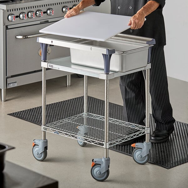 A man using a Metro PrepMate Small Chopped Ingredient Prep Multistation on a white table.