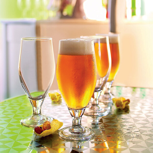 Arcoroc Cervoise stemmed Pilsner glasses filled with beer on a table.