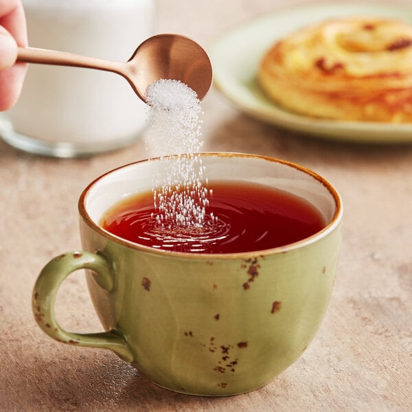 A hand pouring Regal Stevia Leaf Extract into a cup of tea.