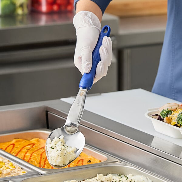 A person in gloves using a Vollrath Jacob's Pride heavy-duty spoon with a blue ergo grip handle to serve mashed potatoes.