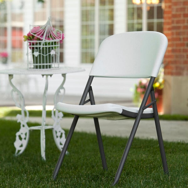 A white Lifetime folding chair set up in a yard.