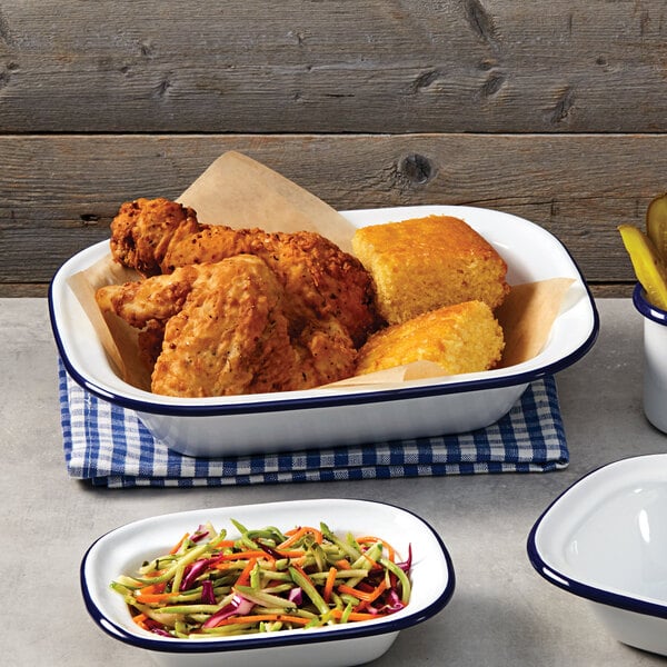 A white rectangular bowl with a blue rim filled with fried chicken next to a white rectangular bowl with a blue rim filled with corn.