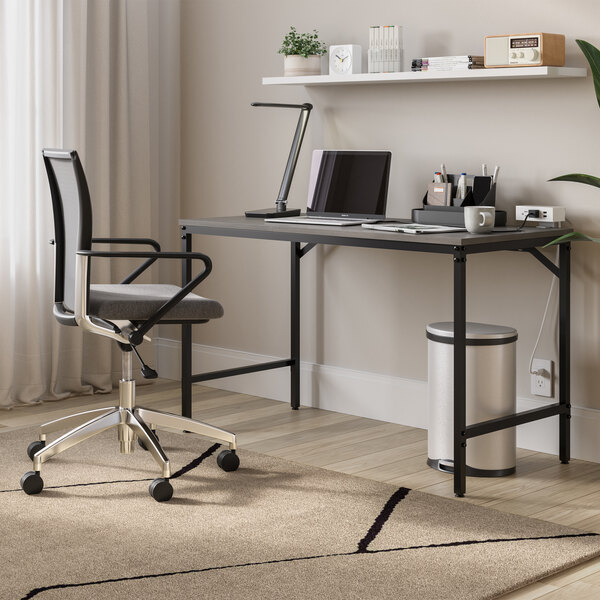 A black LED desk lamp with a multi-pivot adjustable arm and USB port placed on a modern office desk.
