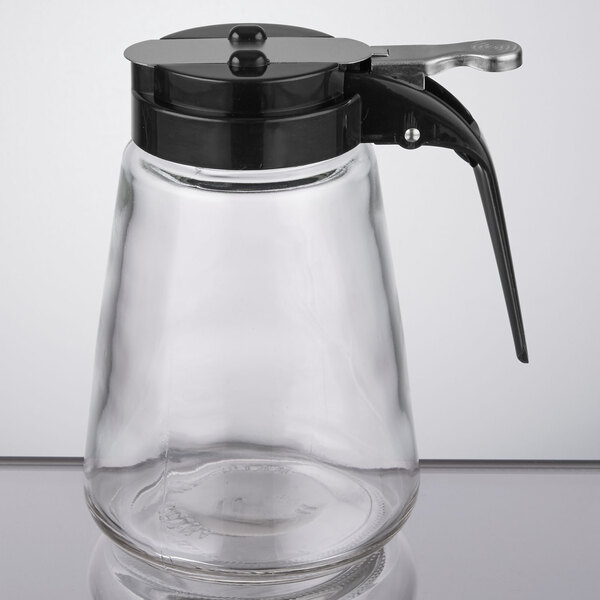 A Tablecraft modern glass syrup dispenser with a black lid.