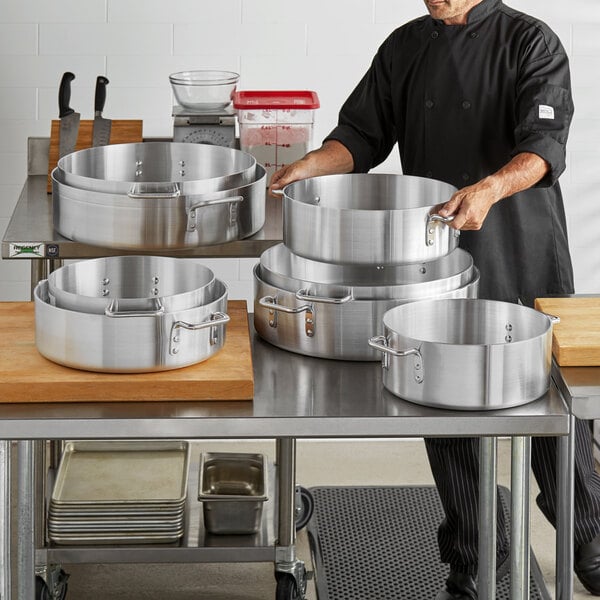 A man in a chef's uniform using a Choice heavy-duty aluminum brazier.