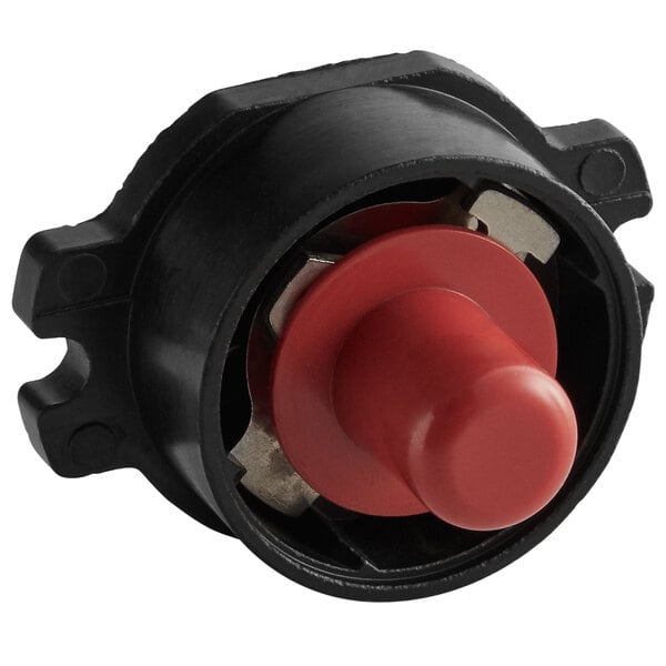A red button on a black device with a round metal ring.