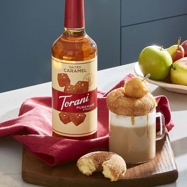 A bottle of Torani Salted Caramel Syrup next to a glass of caramel-flavored coffee.