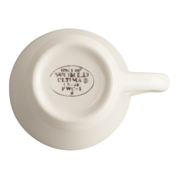 A cream white stoneware cup with a handle, shown upside down to display the manufacturer's mark on the bottom.