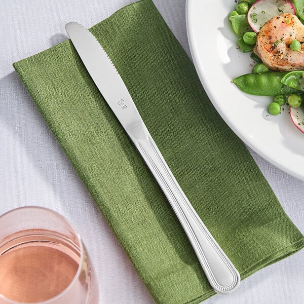 A plate of food with a Libbey stainless steel dinner knife on a table in a farm-to-table restaurant.