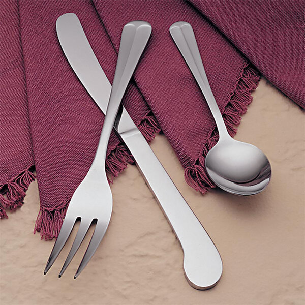 A Libbey medium weight stainless steel dinner fork and spoon on a red napkin.