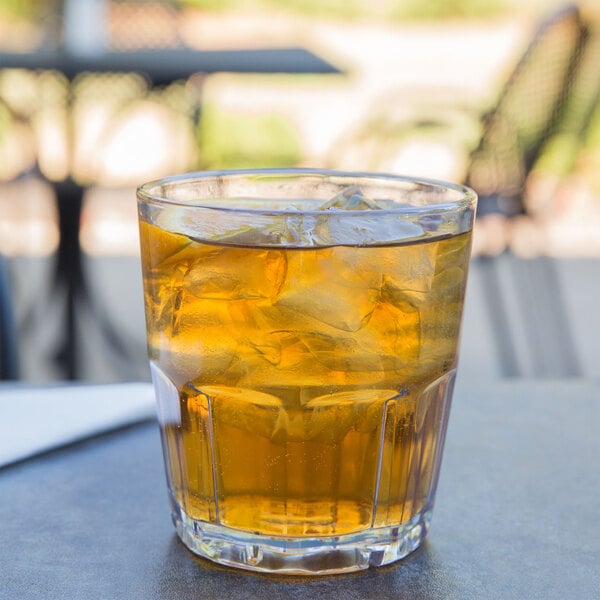 A clear GET Bahama plastic tumbler filled with iced tea on a table.