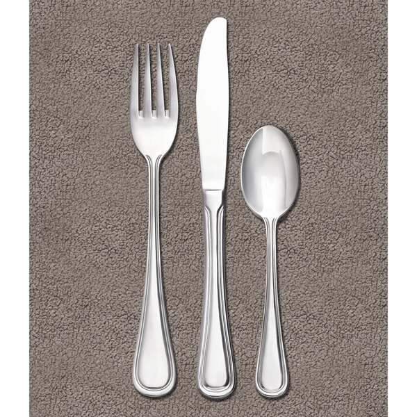 A Libbey stainless steel bouillon spoon on a gray surface.