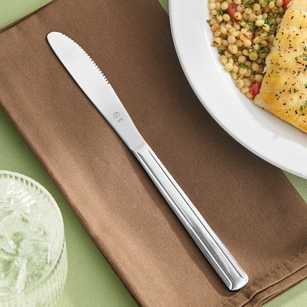 A Libbey stainless steel dinner knife on a plate of food.