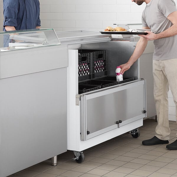 A man putting a milk bottle into a white Beverage-Air milk cooler.