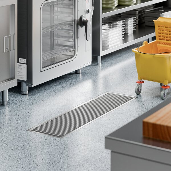 A 12-inch by 48-inch stainless steel floor trough with a grate, designed for commercial kitchen drainage.