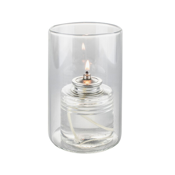 A Sterno clear glass votive candle holder with a lit candle inside.