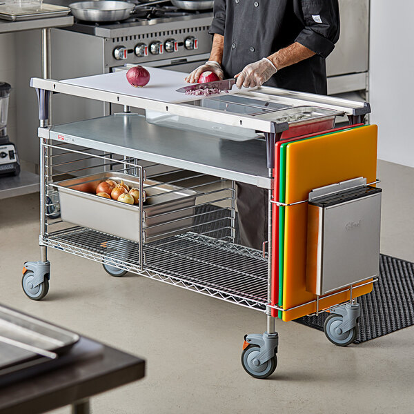 A man using a Metro Prepmate MultiStation cart to cut vegetables on a table in a professional kitchen.