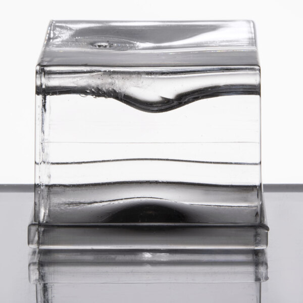 A clear glass cube with a black circle inside filled with clear ice.
