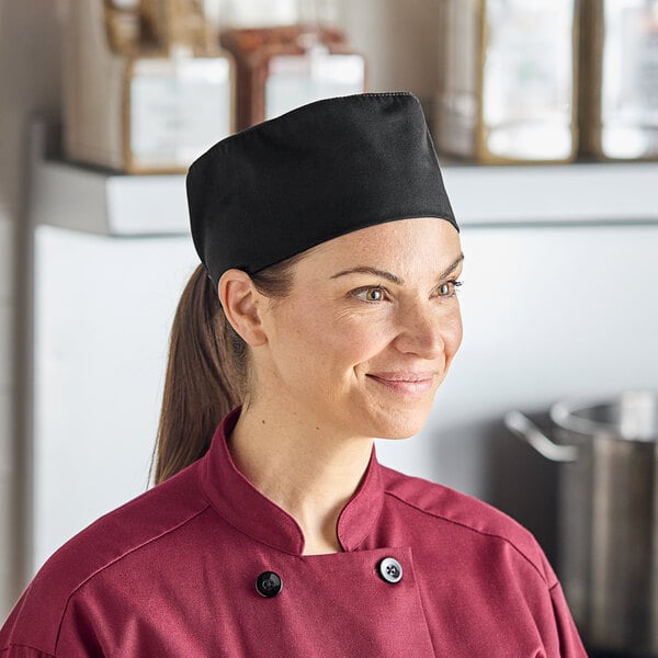 A woman wearing a Mercer Culinary black mesh chef's skull cap smiles.
