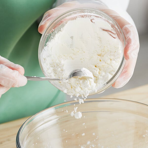 A person pouring Argo corn starch into a bowl of white liquid.