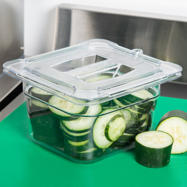 A Carlisle clear plastic container lid with sliced cucumbers inside.