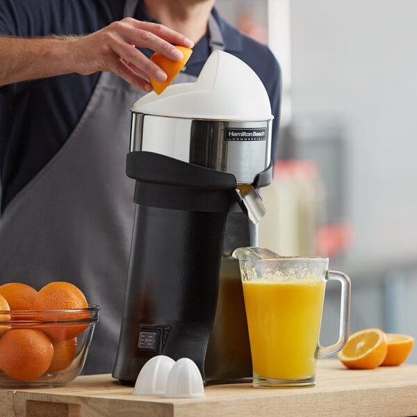 Someone using a juicer to make orange juice