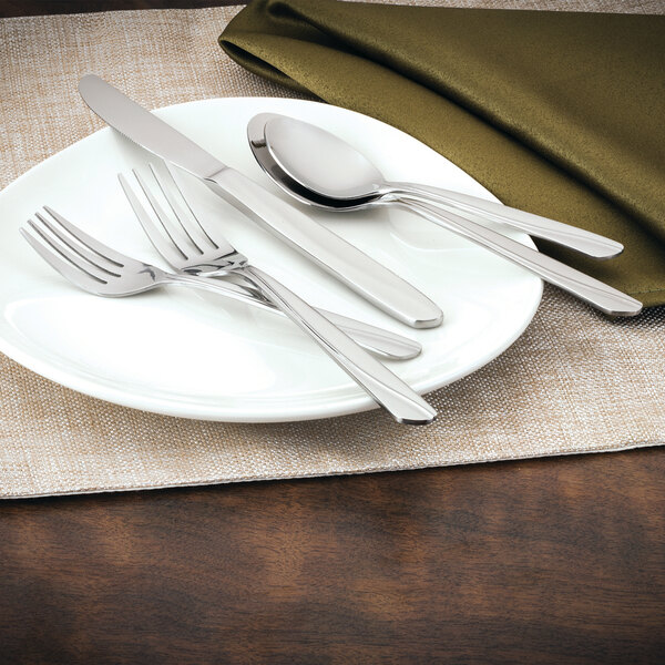 A white plate with a Walco Classic Scroll stainless steel dinner fork on it.