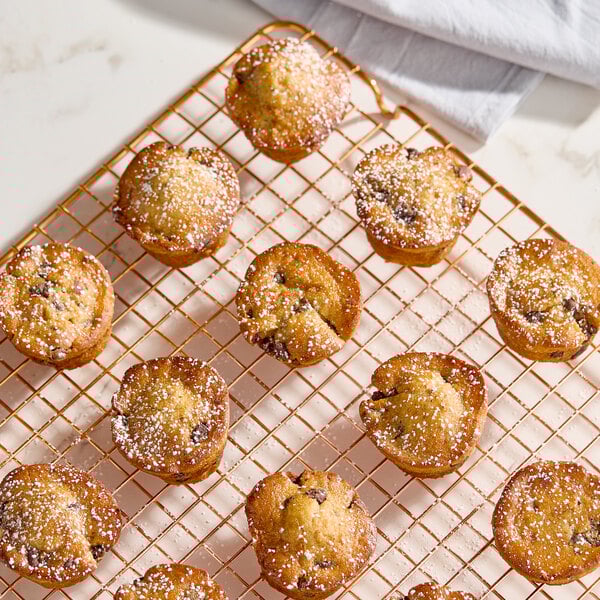 A batch of small muffins dusted with powdered sugar on a cooling rack.