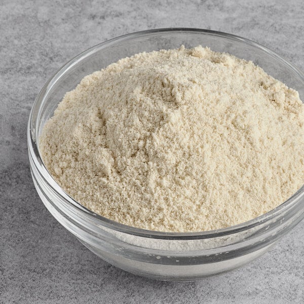 A clear glass bowl filled with finely ground, off-white coconut flour.