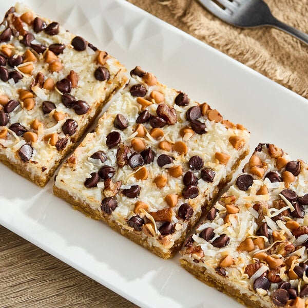 A plate of dessert bars topped with chocolate chips, butterscotch chips, and shredded coconut.