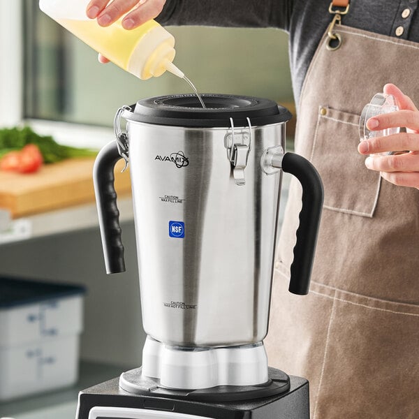 A large stainless steel blender jar with black handles and a secure lid, designed for commercial use.
