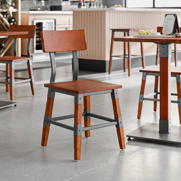 A Lancaster Table & Seating wooden chair with metal legs in a restaurant.