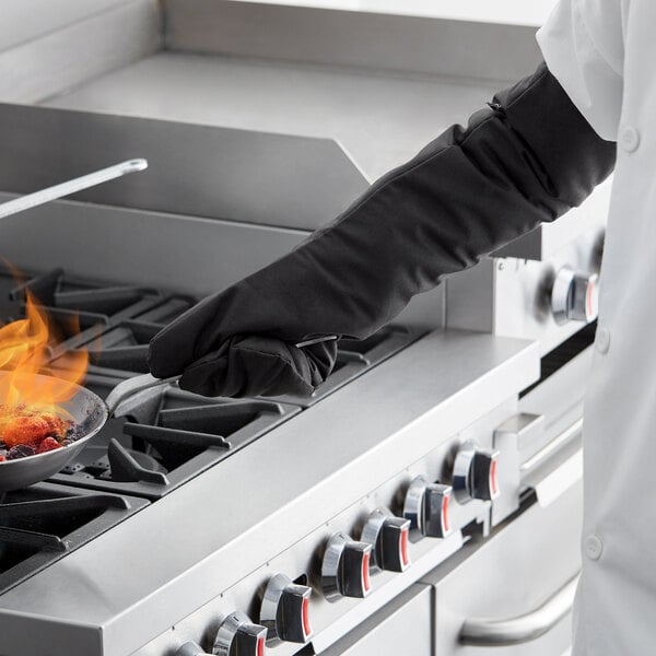 A person wearing SafeMitt oven mitts cooking food on a pan.