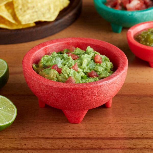 A red Choice Thermal Plastic molcajete bowl of guacamole with chips.