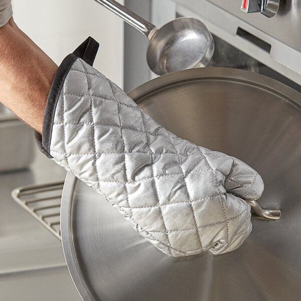 A person wearing a 15" silicone-coated oven mitt and holding a pan.
