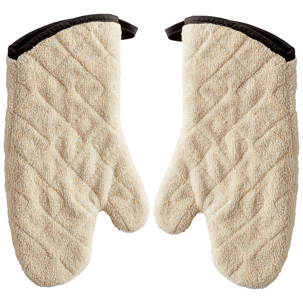 A pair of beige terry oven mitts with black trim.