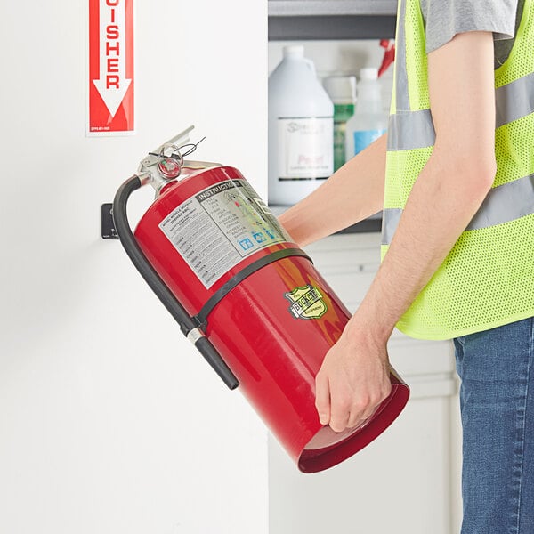 A man in a reflective vest holding a Buckeye ABC fire extinguisher.