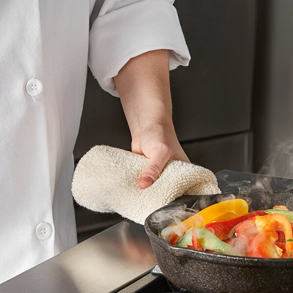 A person using a SafeMitt to grab a pan of food from the oven.
