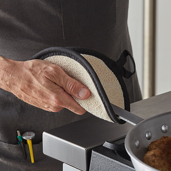 A person using a SafeMitt pot holder to hold a hot pan