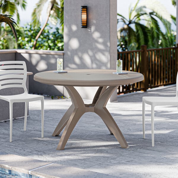 A Grosfillex round resin pedestal table with chairs on an outdoor patio.