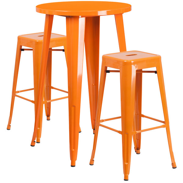 An orange metal bar height table with two square orange stools.