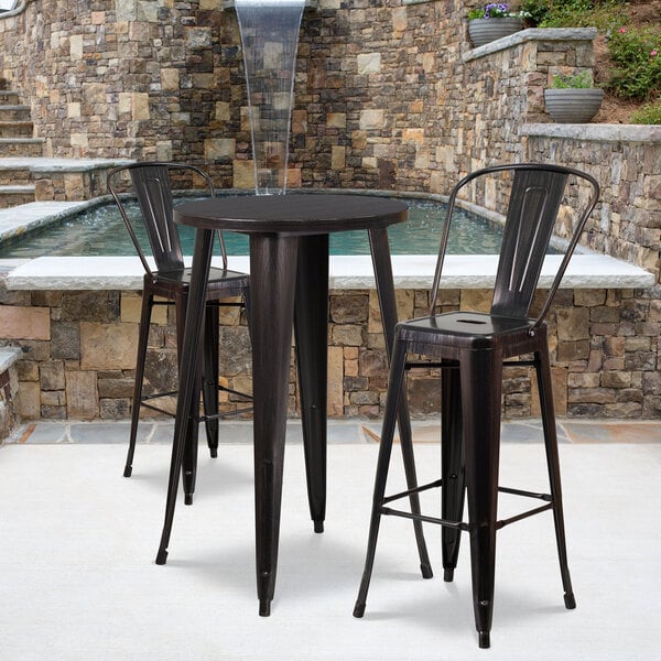 A Flash Furniture black metal bar height table with two black metal bar stools on an outdoor patio.