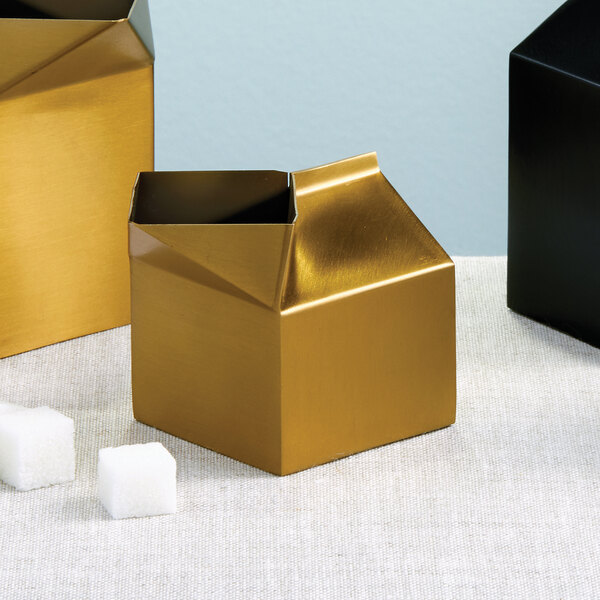 A gold satin stainless steel milk carton with a hole in the middle.