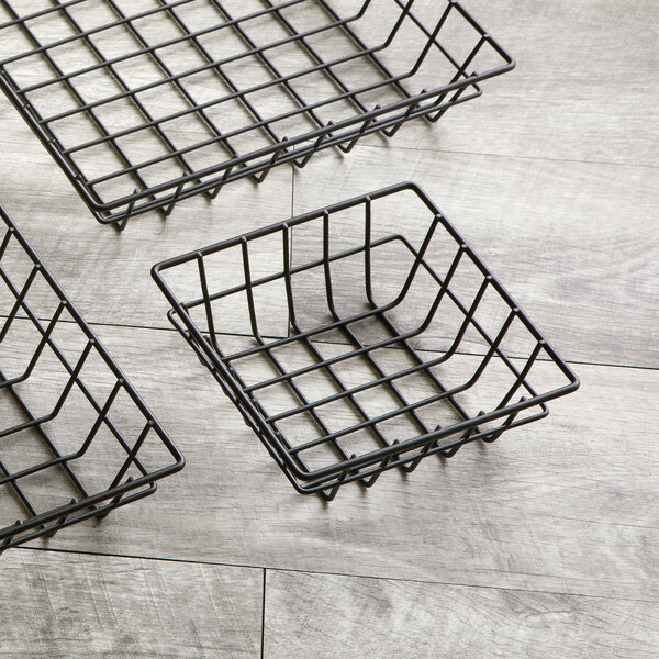 Three American Metalcraft black square wire baskets on a wood surface.