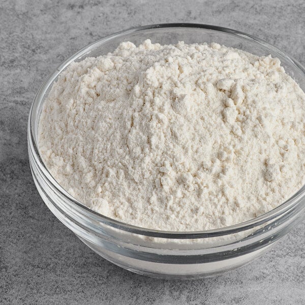 A glass bowl filled with organic unbleached all-purpose flour.