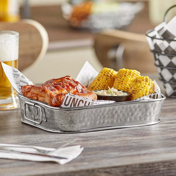 A rectangular hammered stainless steel food serving tub filled with corn on the cob.