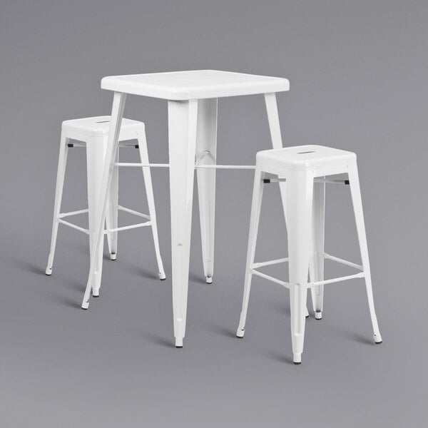 A white metal bar height table with two white square backless stools.