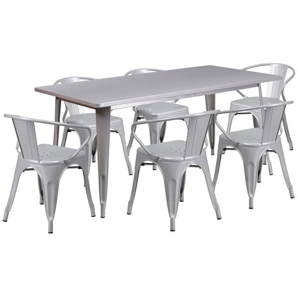 A silver rectangular metal table with a white background surrounded by six white plastic chairs.