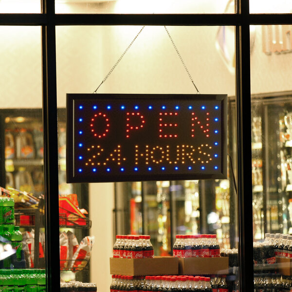 A rectangular LED sign that says "Open 24 Hours" with lights on it.