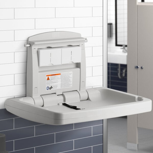 A Rubbermaid baby changing station with a white tray and black strap on a white plastic surface.